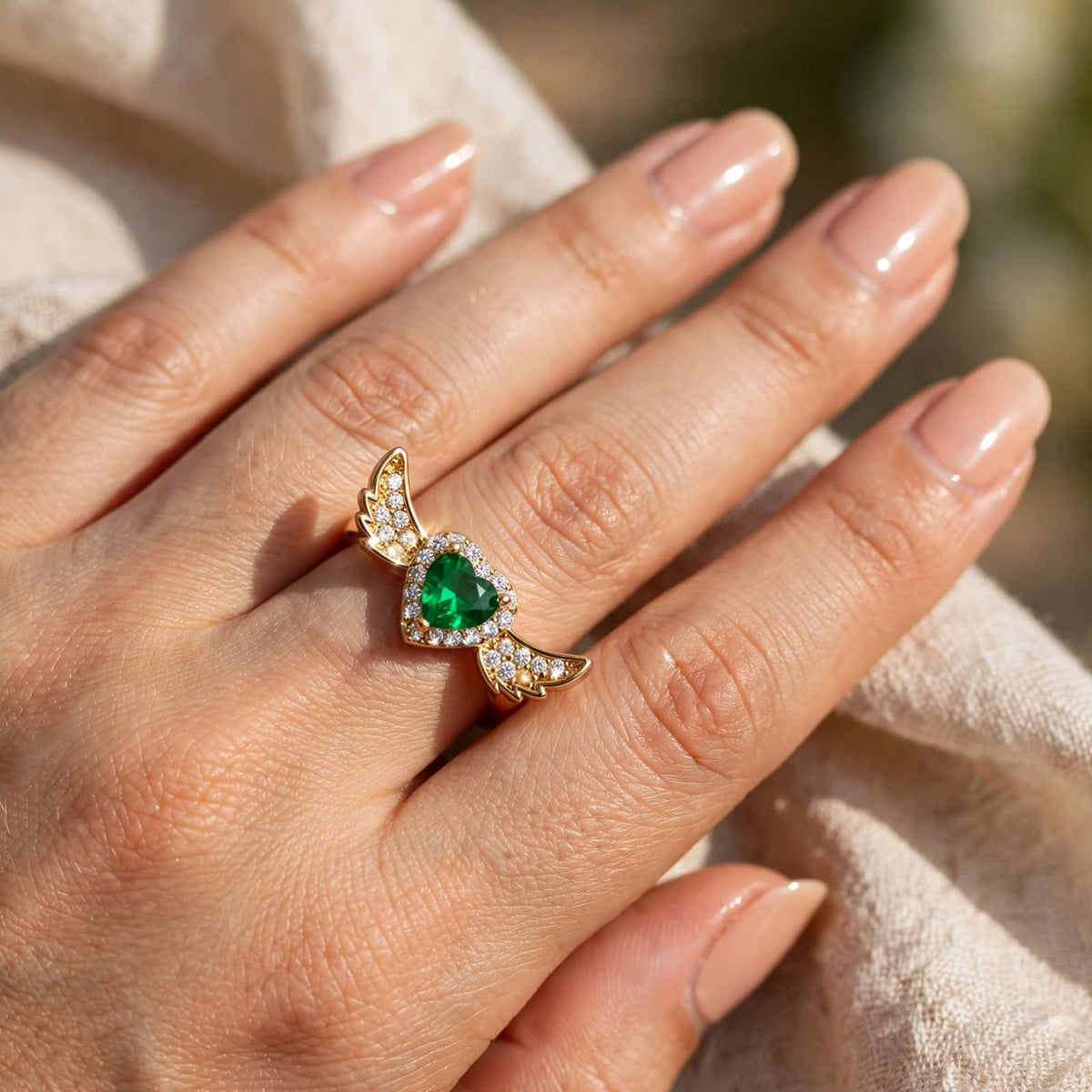Emerald Green Heart Angel Wings Adjustable Ring worn on finger in sunlight