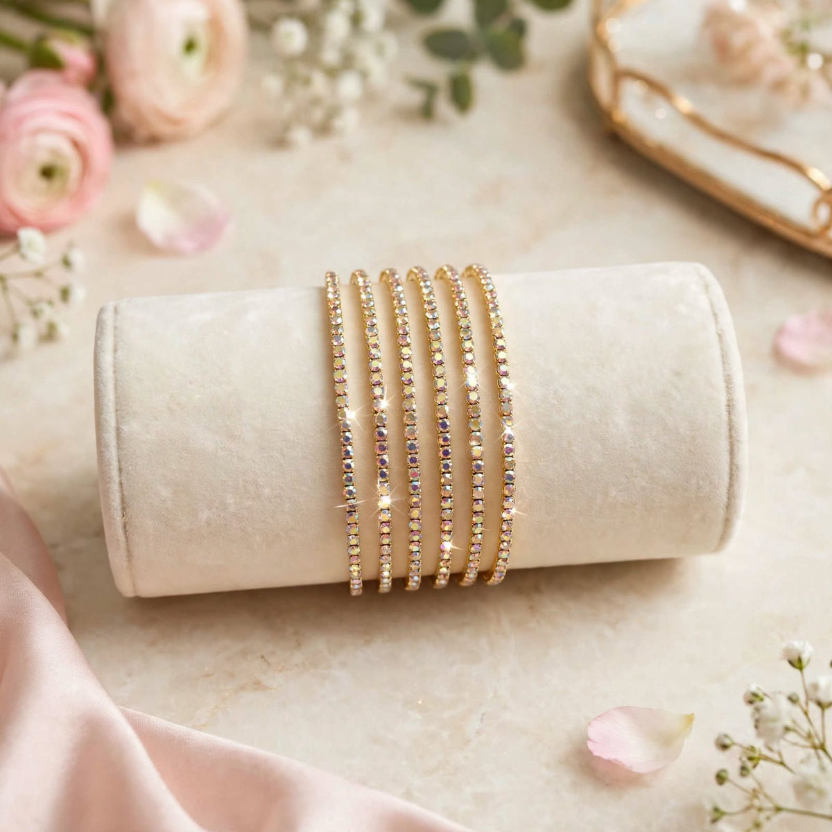 Gold AB Rainbow Rhinestone Elastic Bracelet Set of 6 on velvet display roll with floral backdrop