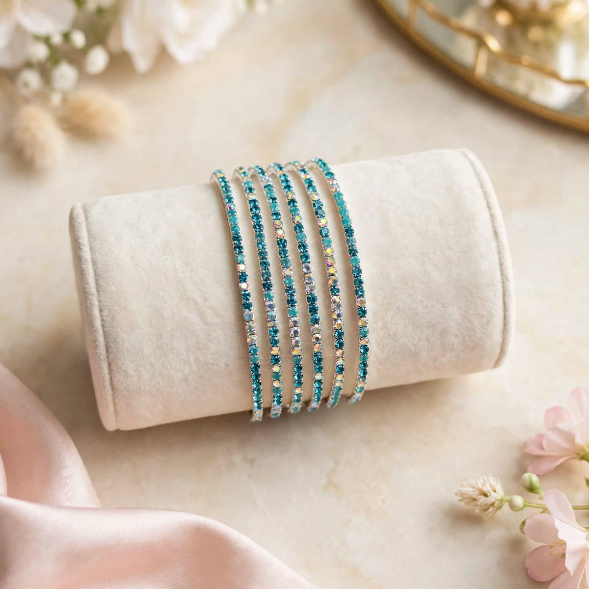 Teal and Silver AB Rhinestone Elastic Bracelet Set of 6 on velvet display roll with floral backdrop