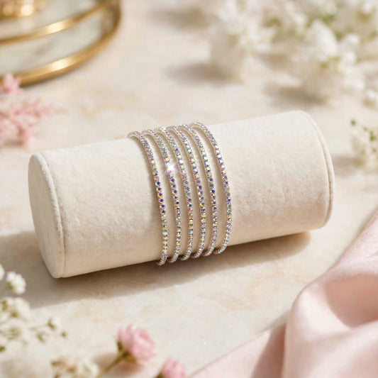 Silver AB Rainbow Rhinestone Elastic Bracelet Set of 6 on velvet display roll with floral backdrop